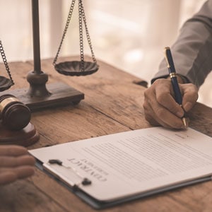 Two individuals reviewing and signing a legal contract, with scales of justice in the background symbolizing personal injury claim