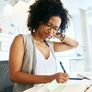 Woman experiencing neck pain while writing notes, illustrating a personal injury claim process