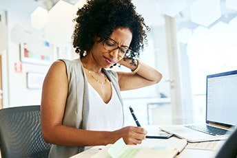 Woman experiencing neck pain while writing notes, illustrating a personal injury claim process