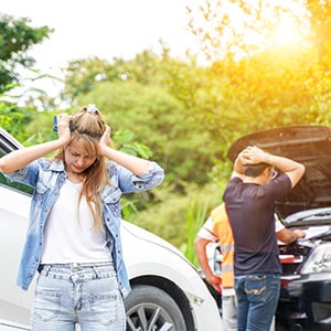 A woman stands beside an open car hood, assessing the vehicle's condition in St. Tammany Parish